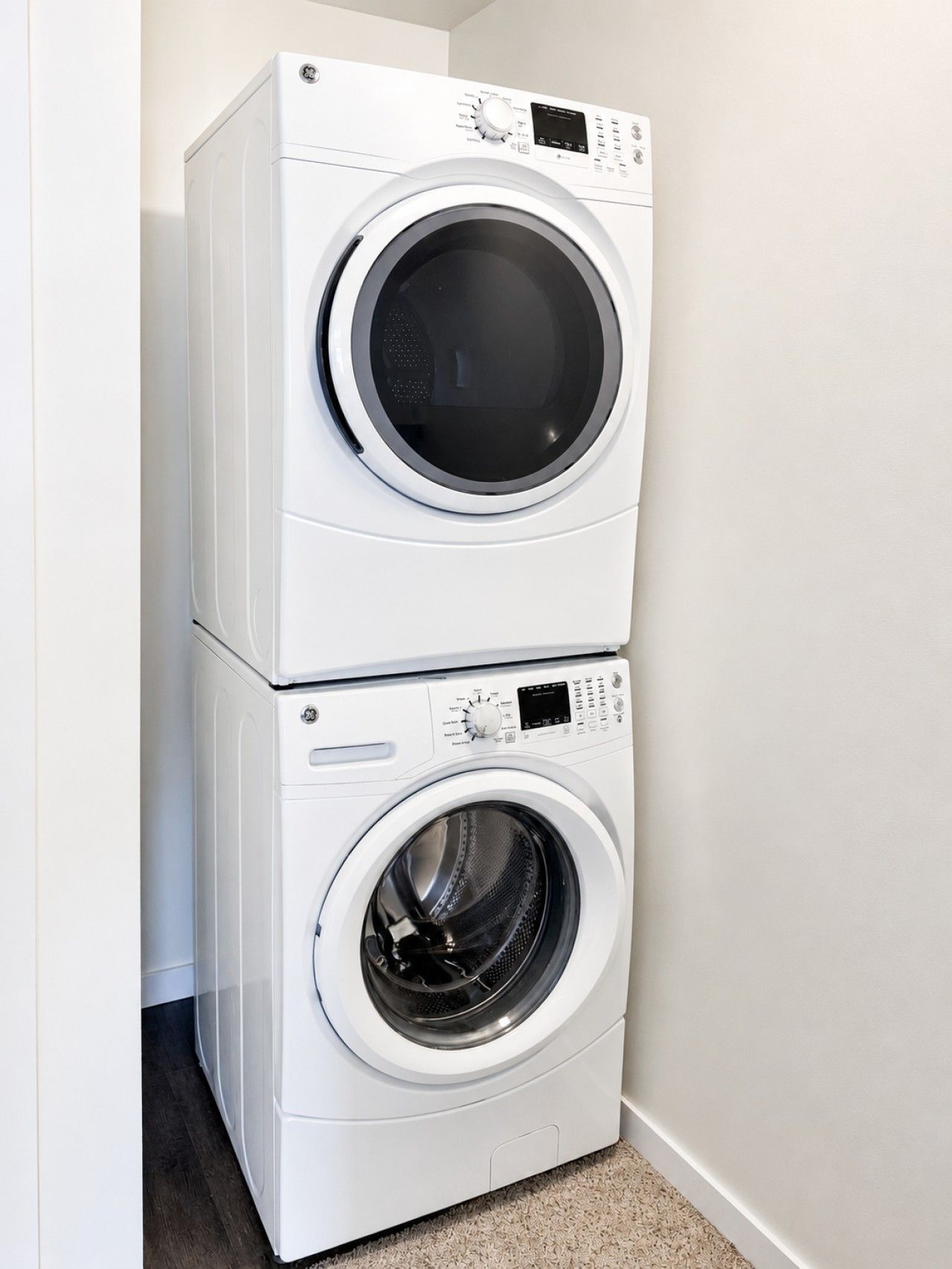 Une machine à laver et un sèche-linge superposés, placés dans un coin de la pièce.