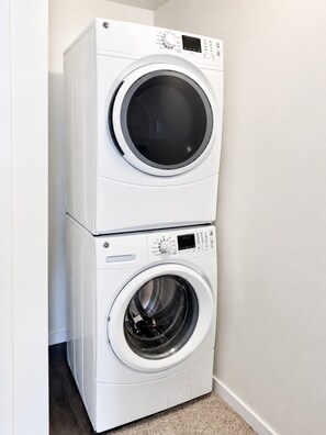 Une machine à laver et un sèche-linge superposés, placés dans un coin de la pièce.