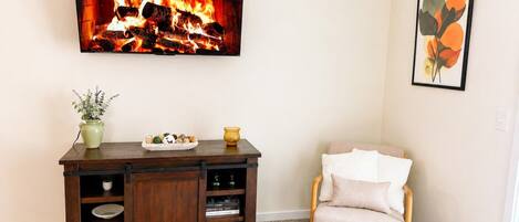 A room with a fireplace, a wooden cabinet, a chair, and a framed picture on the wall.