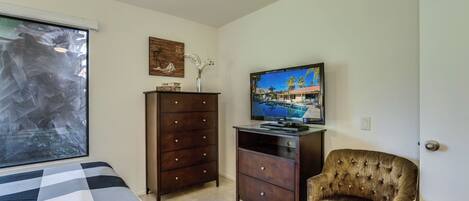 A bedroom with a bed, a dresser, a television, and a chair.