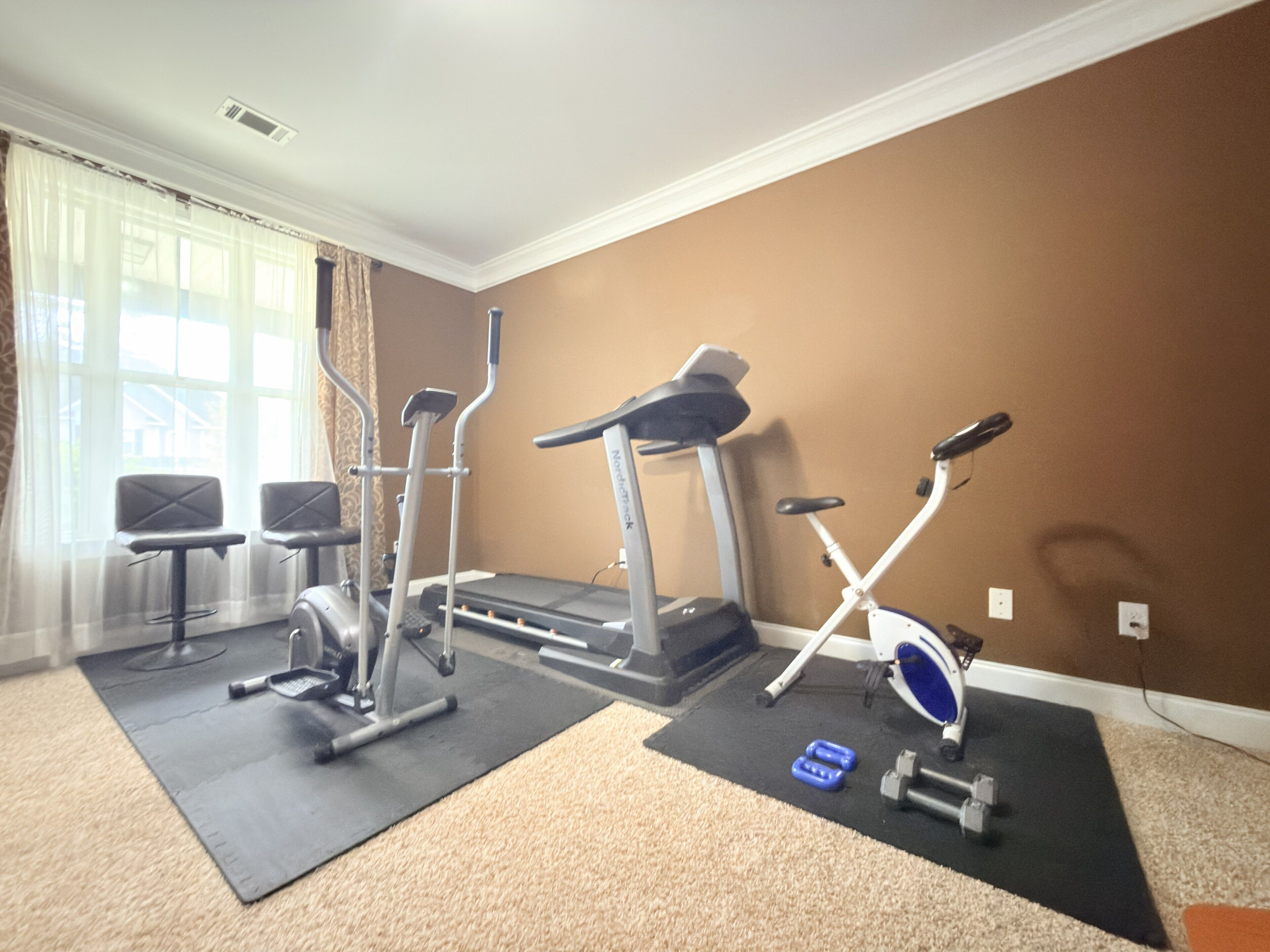 Un gimnasio en casa con equipo de ejercicio, una cinta de correr y una bicicleta estática.