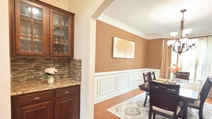 A kitchen with wooden cabinets, a granite countertop, and a vase with flowers. - Elegant 5BR/4BA Masters Rental – Just 7 Miles from Augusta National (Martinez)