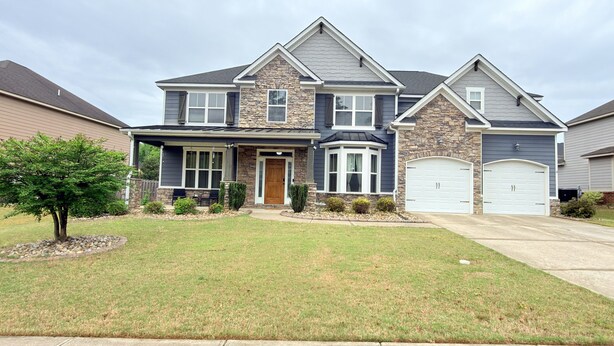 A two-story house with a stone facade, a front porch, and a garage. - Elegant 5BR/4BA Masters Rental – Just 7 Miles from Augusta National (Martinez)