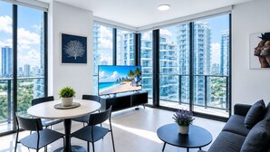 A modern living room with a large TV, a dining table, and a sofa. - 2408 New Luxury Downtown Retreat, Gym, & Prime Location 1B1B (Miami)