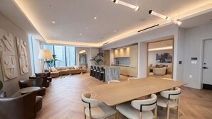 A modern hotel lobby with a large wooden conference table, comfortable seating, and a view of the city. - 2408 New Luxury Downtown Retreat, Gym, & Prime Location 1B1B (Miami)