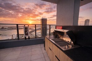 A balcony with a view of a sunset over a cityscape, a grill, and a fire extinguisher. - 2408 New Luxury Downtown Retreat, Gym, & Prime Location 1B1B (Miami)