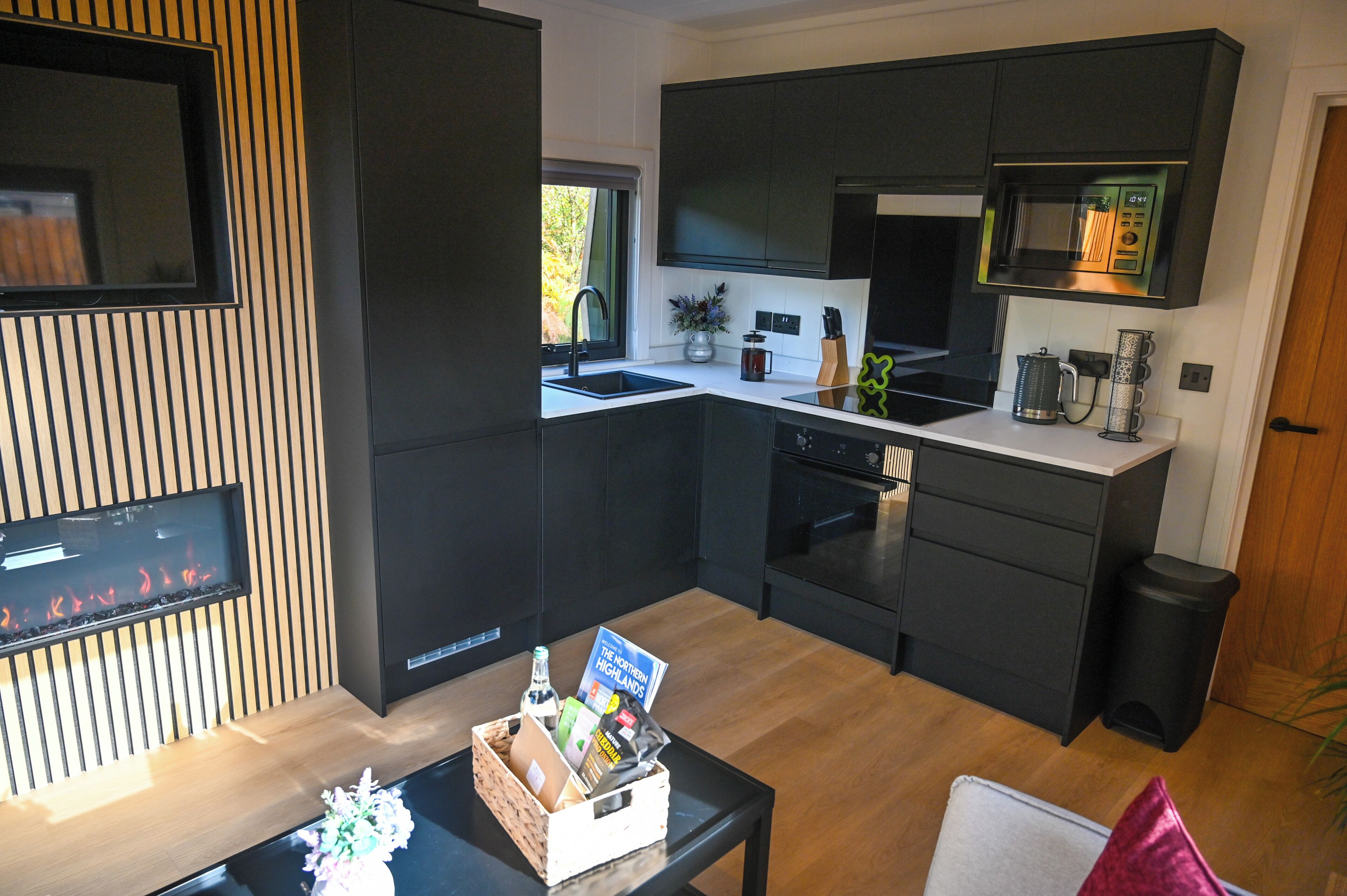 A modern kitchen with dark cabinetry, a built-in microwave, and a large window.