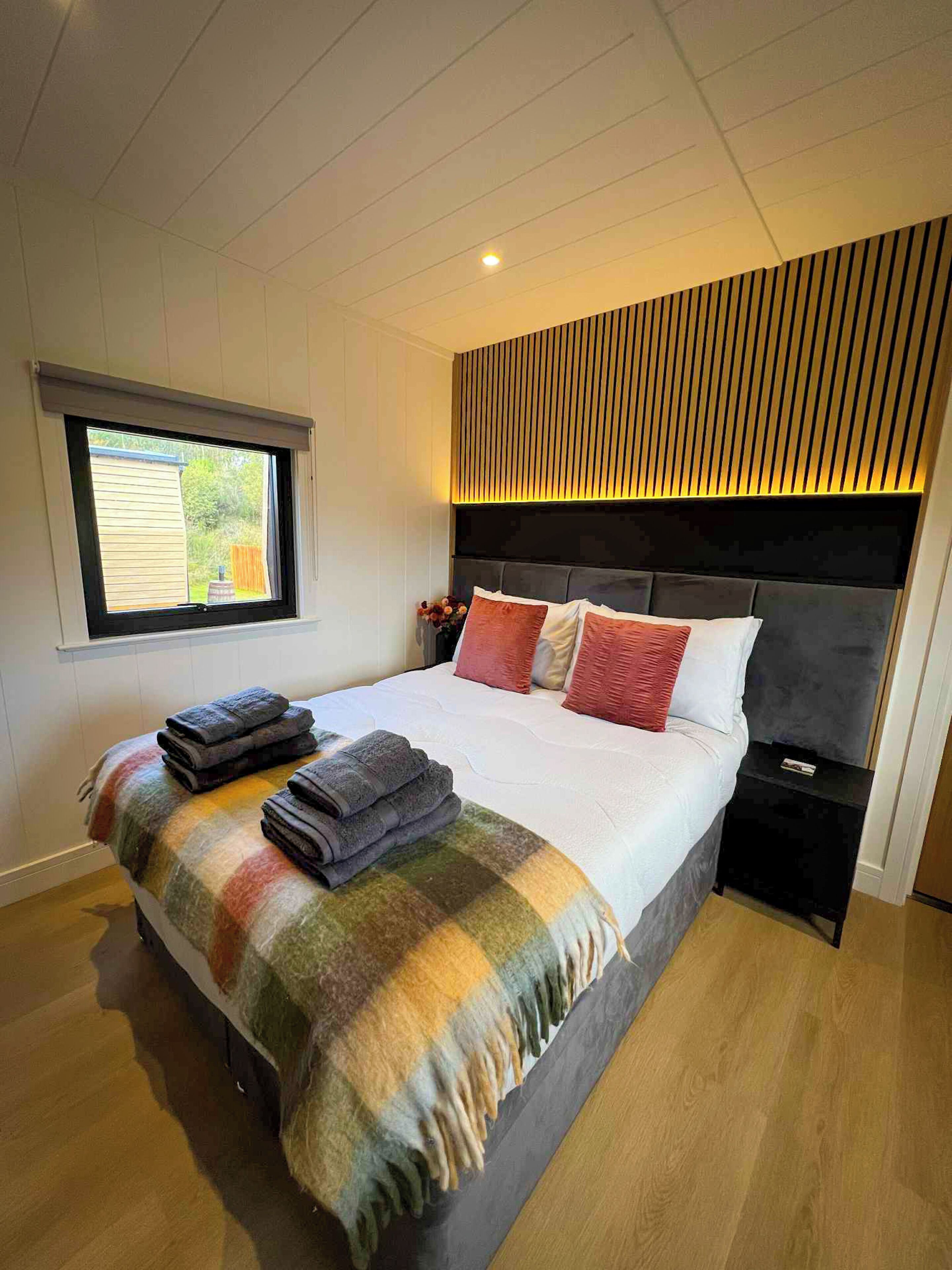 Une chambre à coucher comprenant un lit, une table de chevet, une fenêtre et une tête de lit fixée au mur.