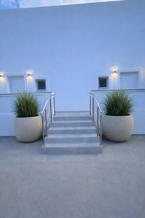 A modern building with a concrete floor, a metal staircase, and two large potted plants. - Villa 'Aqua Blue 2' with Private Pool and Sea View (Amoopi)