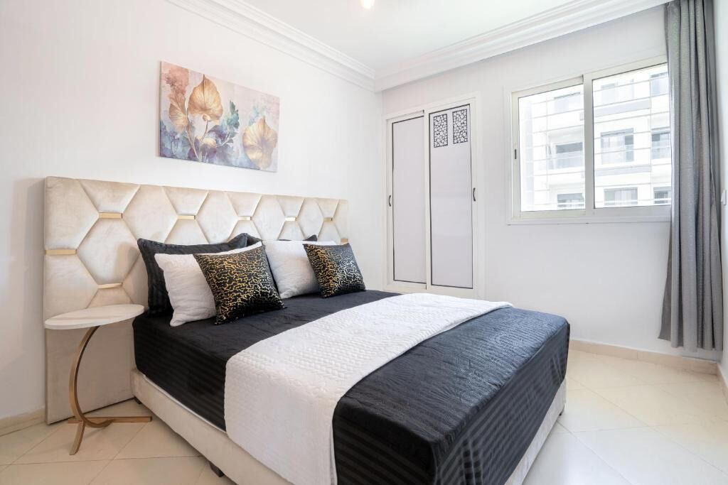 Une chambre à coucher avec un lit, une table de chevet, un tableau, une armoire et une fenêtre.