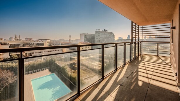 Un balcón con vista a una piscina y edificios circundantes.