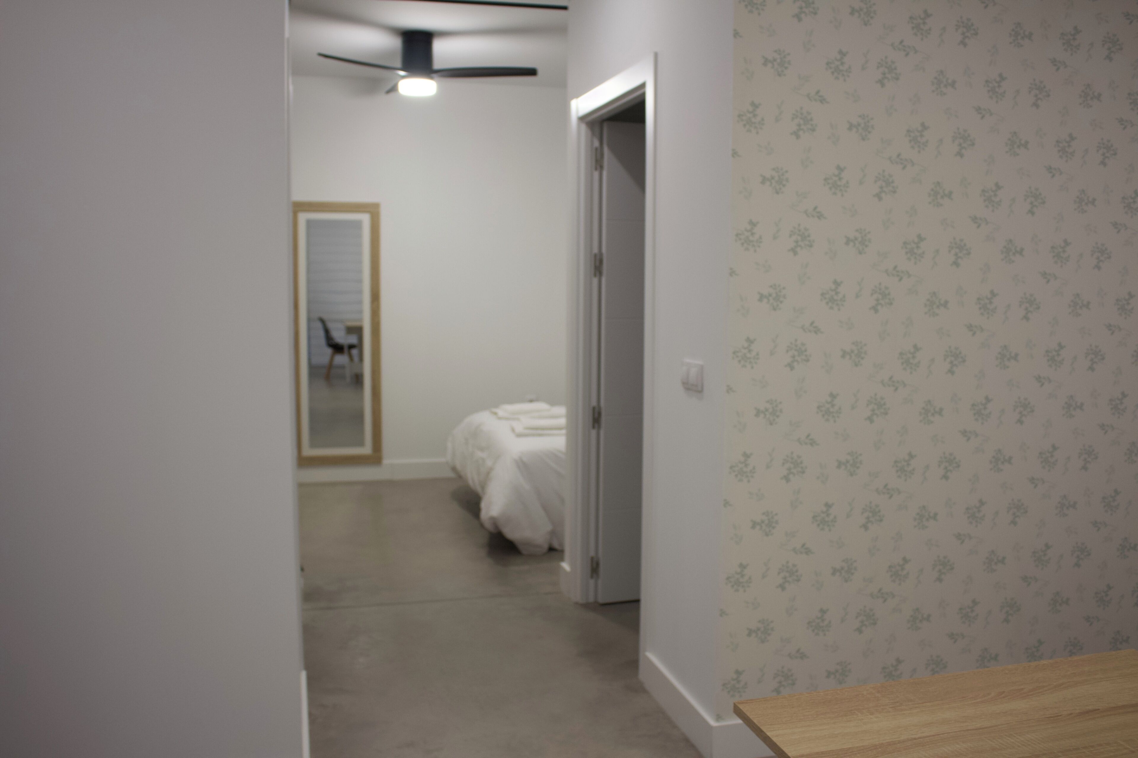 A hallway with a bed, a door, and a ceiling fan.