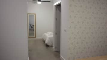 A hallway with a bed, a door, and a ceiling fan.
