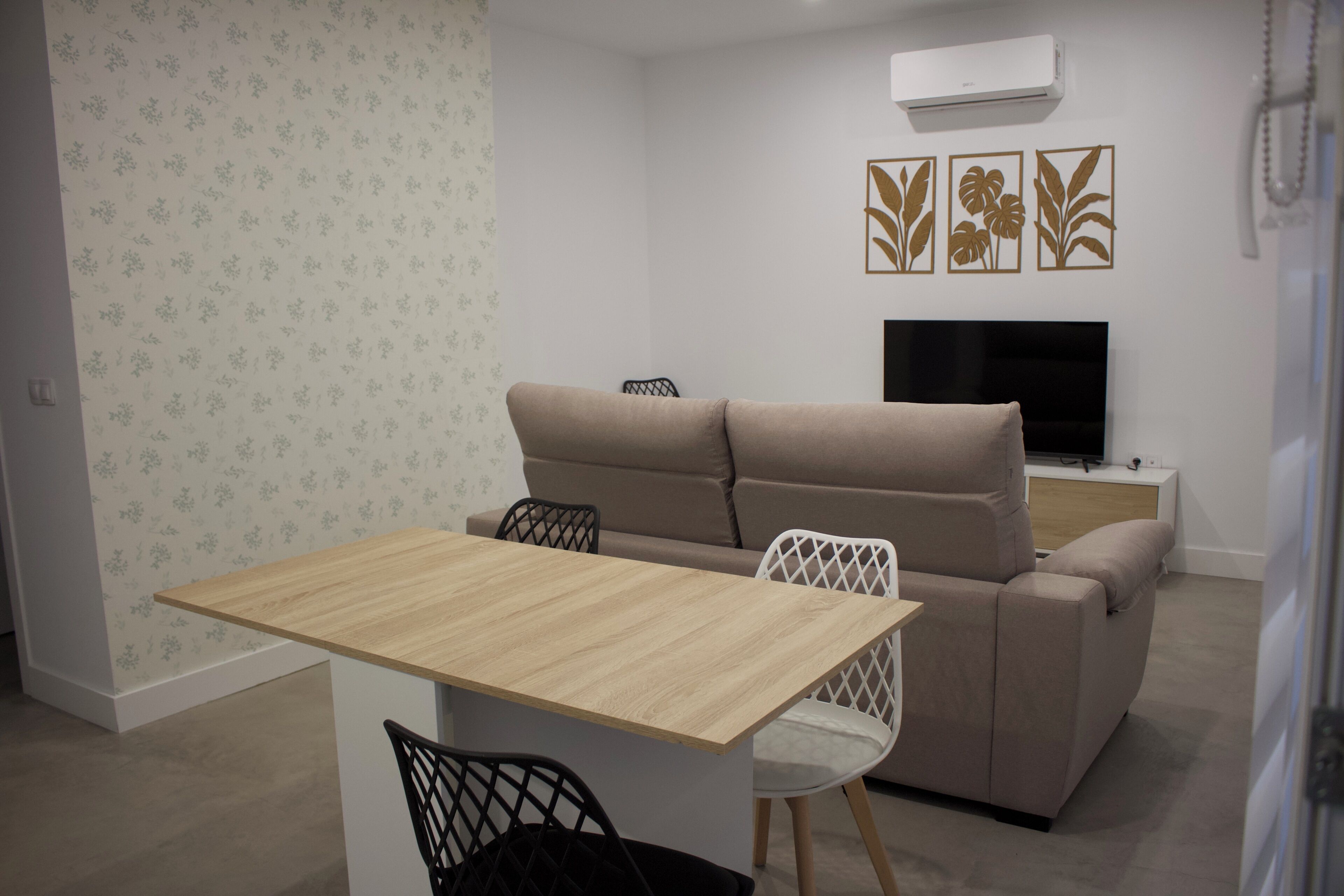 A modern living room with a sofa, a TV, and a dining table.