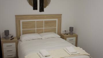 Un dormitorio con una cama, mesitas de noche, un adorno circular en la pared y un ventilador de techo.