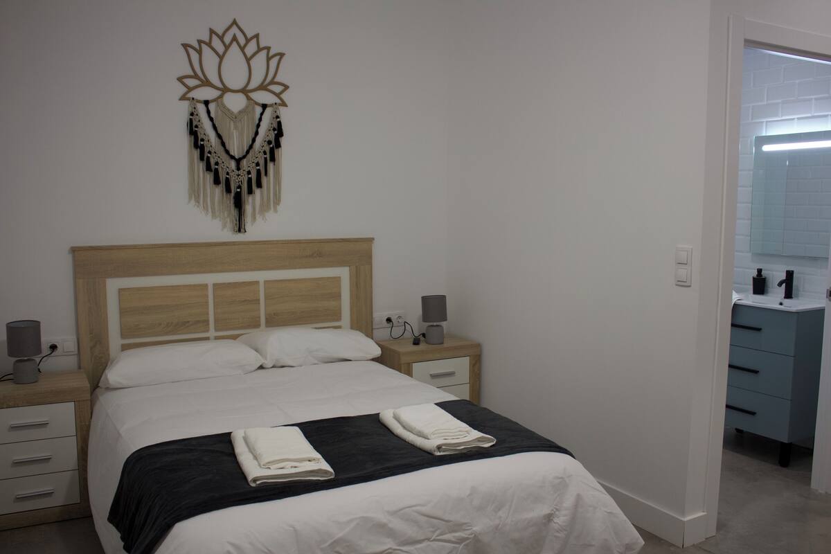 Un lit bien fait, avec une tête de lit en bois, des lampes de chevet et un élément décoratif mural.