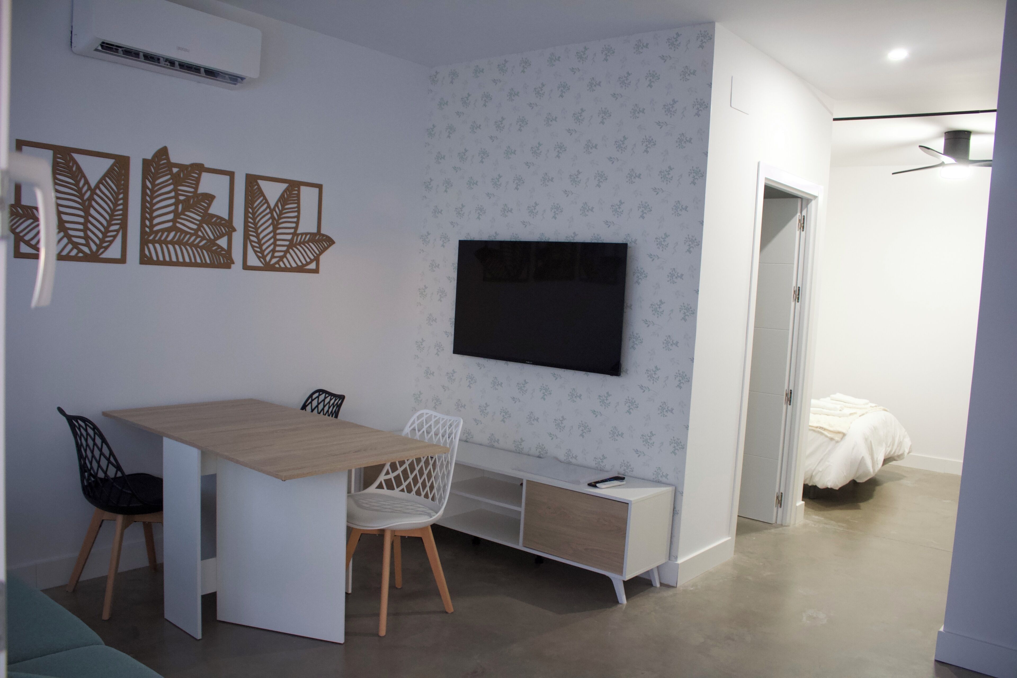 Una habitación pequeña con una cama, un escritorio y un televisor.