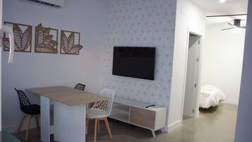 Una habitación pequeña con una cama, un escritorio y un televisor.