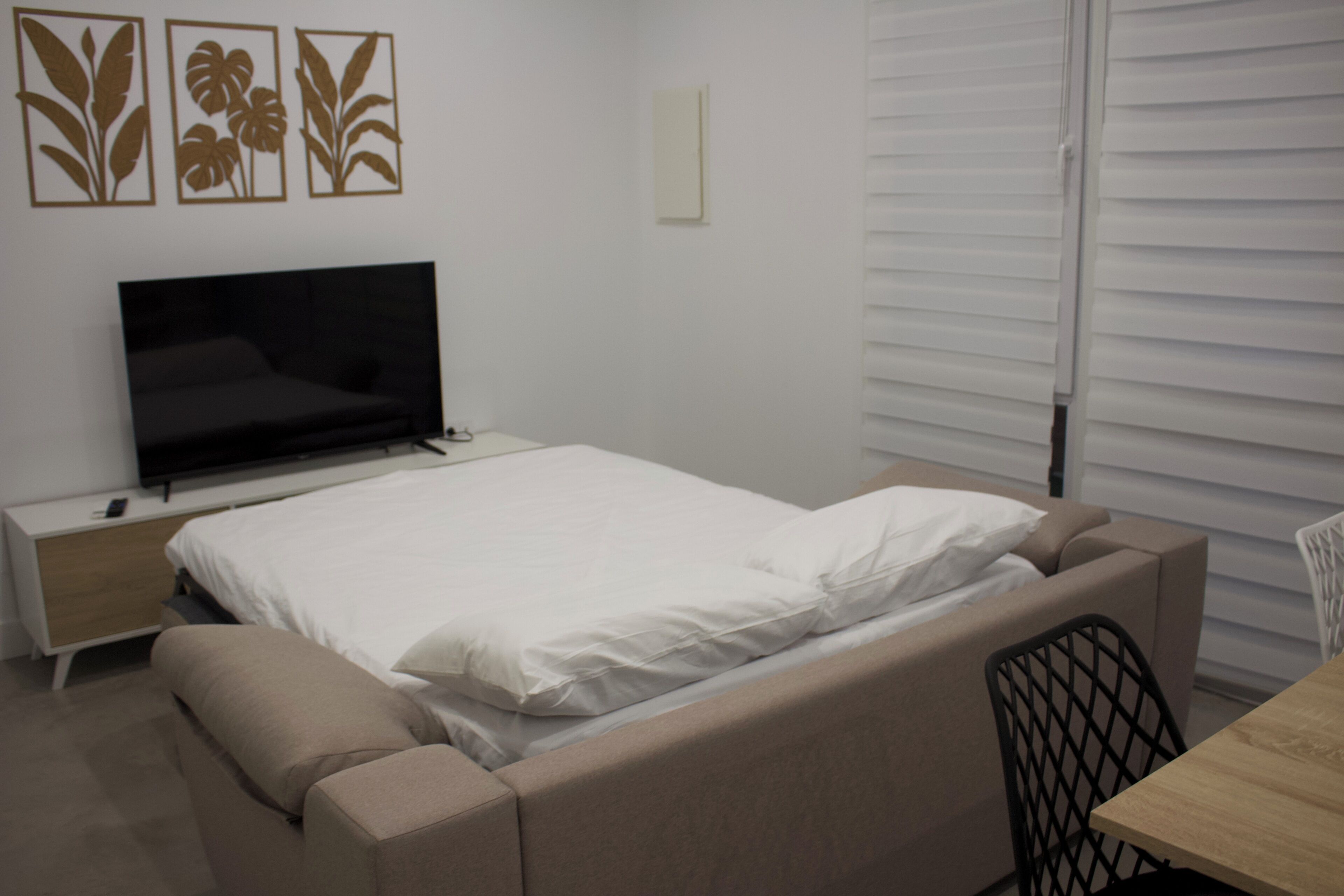 Un dormitorio con cama, televisión, escritorio y silla.