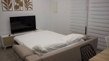 Un dormitorio con cama, televisión, escritorio y silla.
