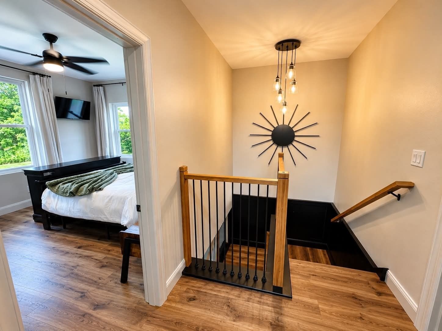 Une chambre avec un lit, un ventilateur de plafond, une télévision et une vue sur la verdure environnante.
