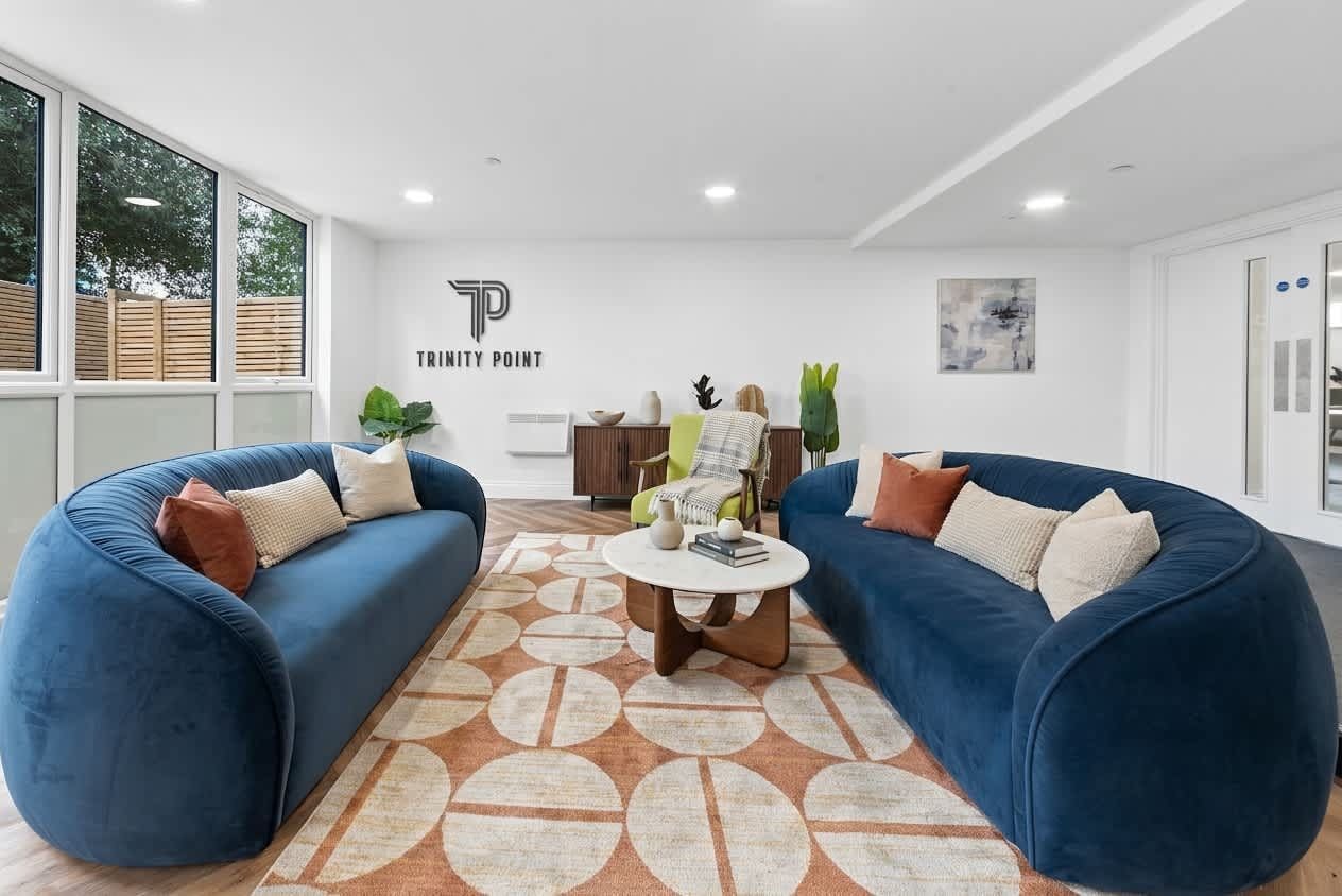 A modern living room with two blue sofas, a coffee table, and a patterned rug.