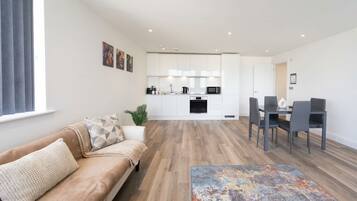 A modern living room with a sofa, a coffee table, and a dining area with chairs.