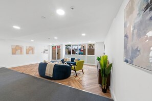 A modern interior with a seating area, a large artwork on the wall, and a view through the window. - Modern 2-Bed Gravesend Apt with Games Room (Gravesend)