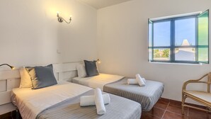 A hotel room with two beds, a window with a view, a chair, and a wall-mounted light fixture. - #361 Quinta Brito Lima D (Paderne)
