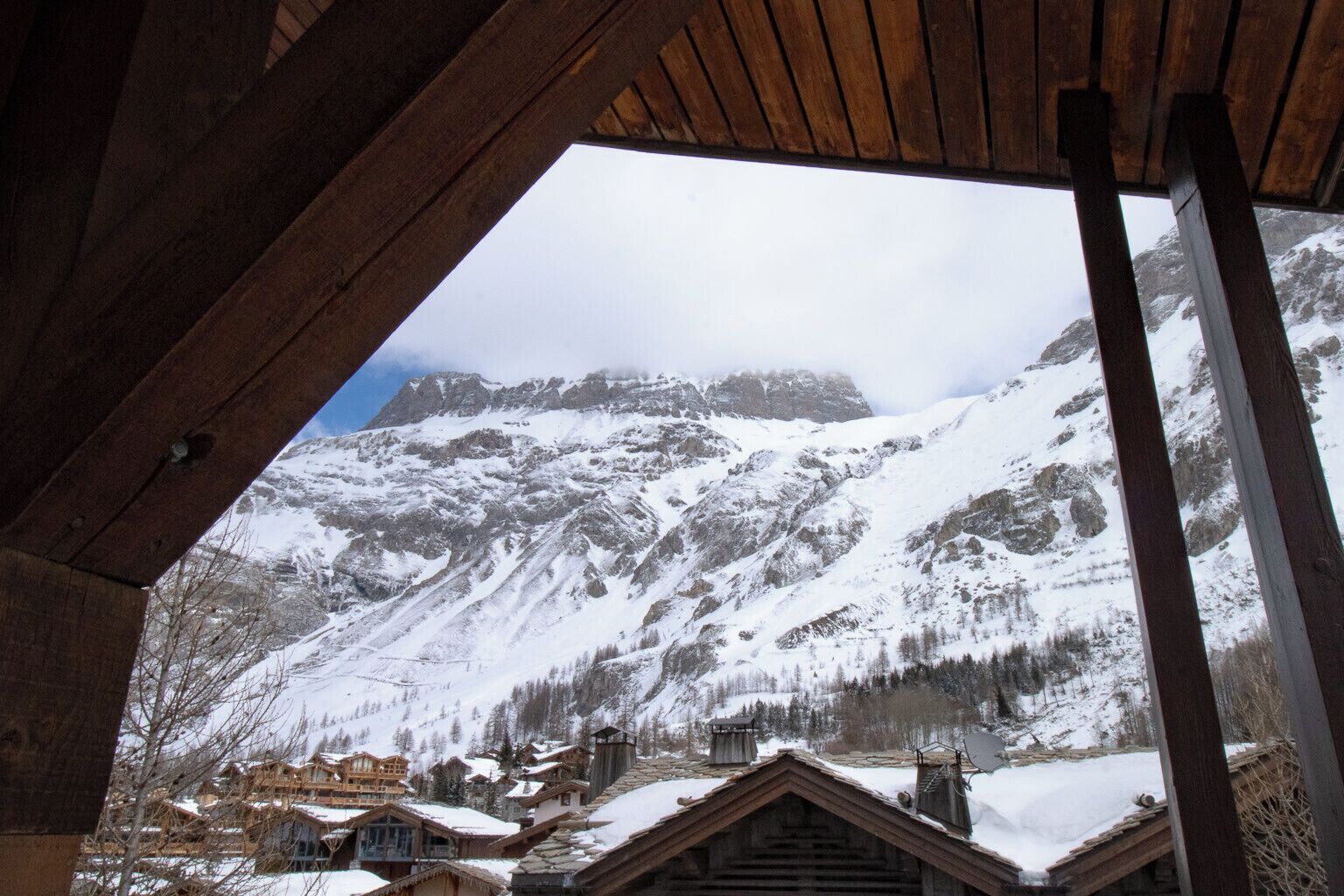 A mountain cabin with a wooden interior and a view of snow-covered mountains.