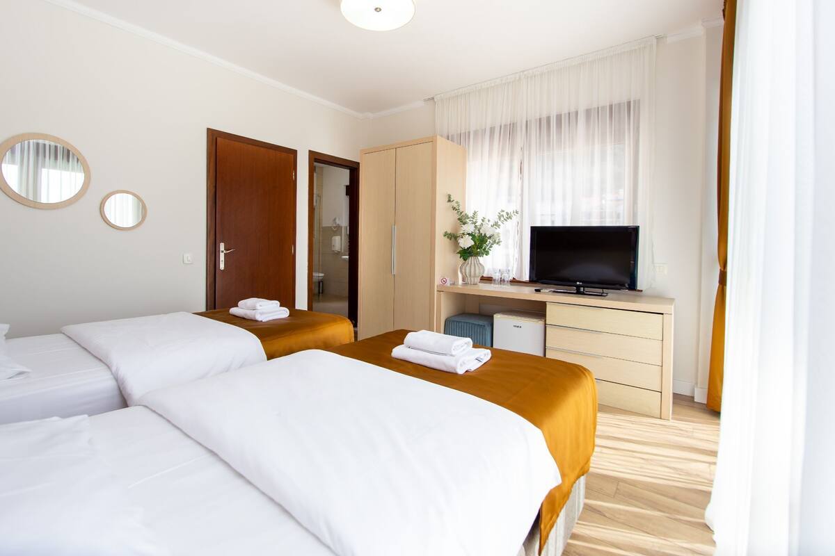 Una habitación de hotel con dos camas, televisión, escritorio y armario.