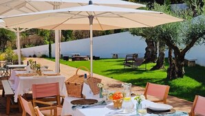 An outdoor dining area with tables, chairs, and umbrellas. - Casaspensadas (Porto de Mos)