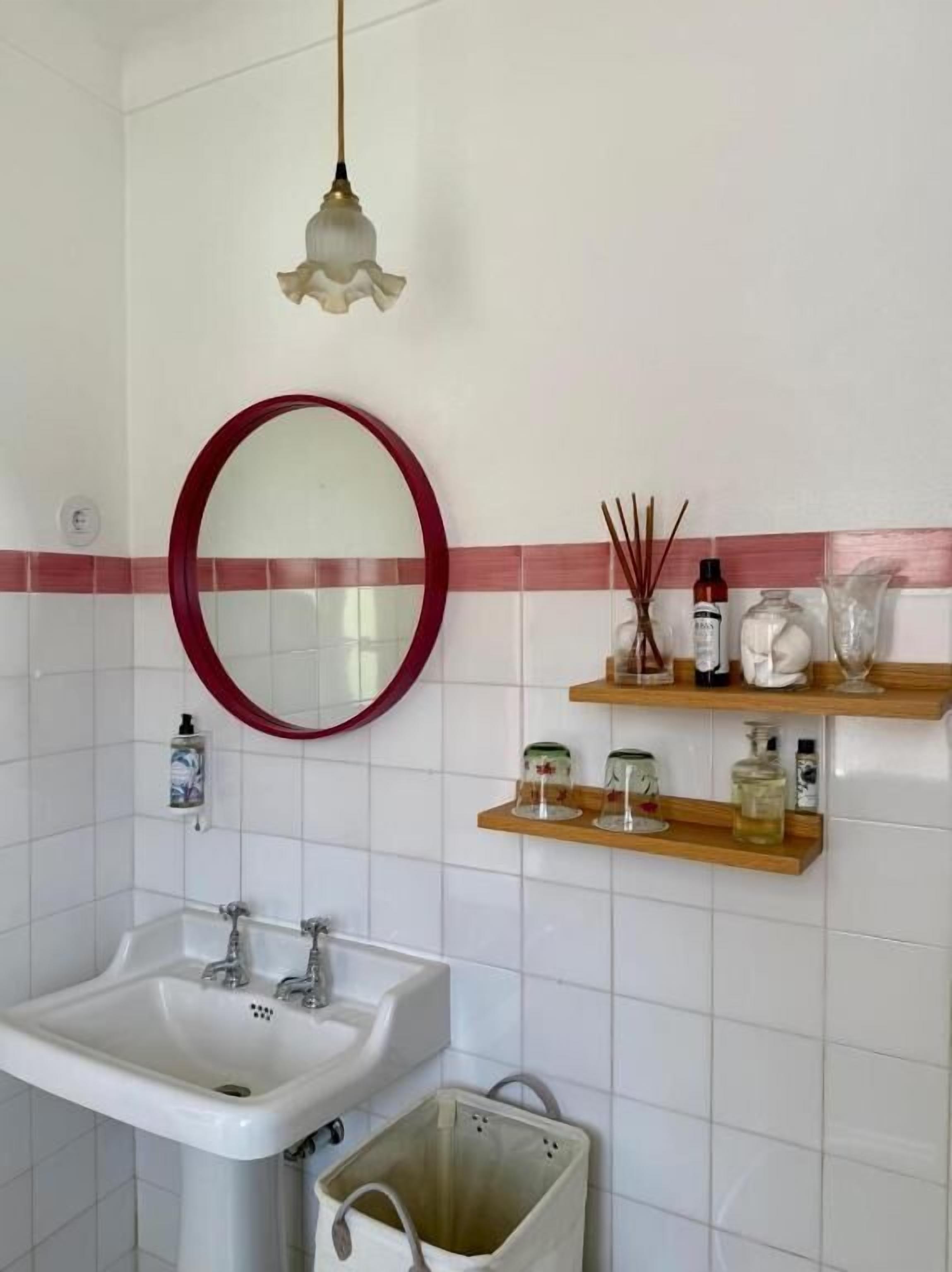 A bathroom with a sink, mirror, and shelves with toiletries.