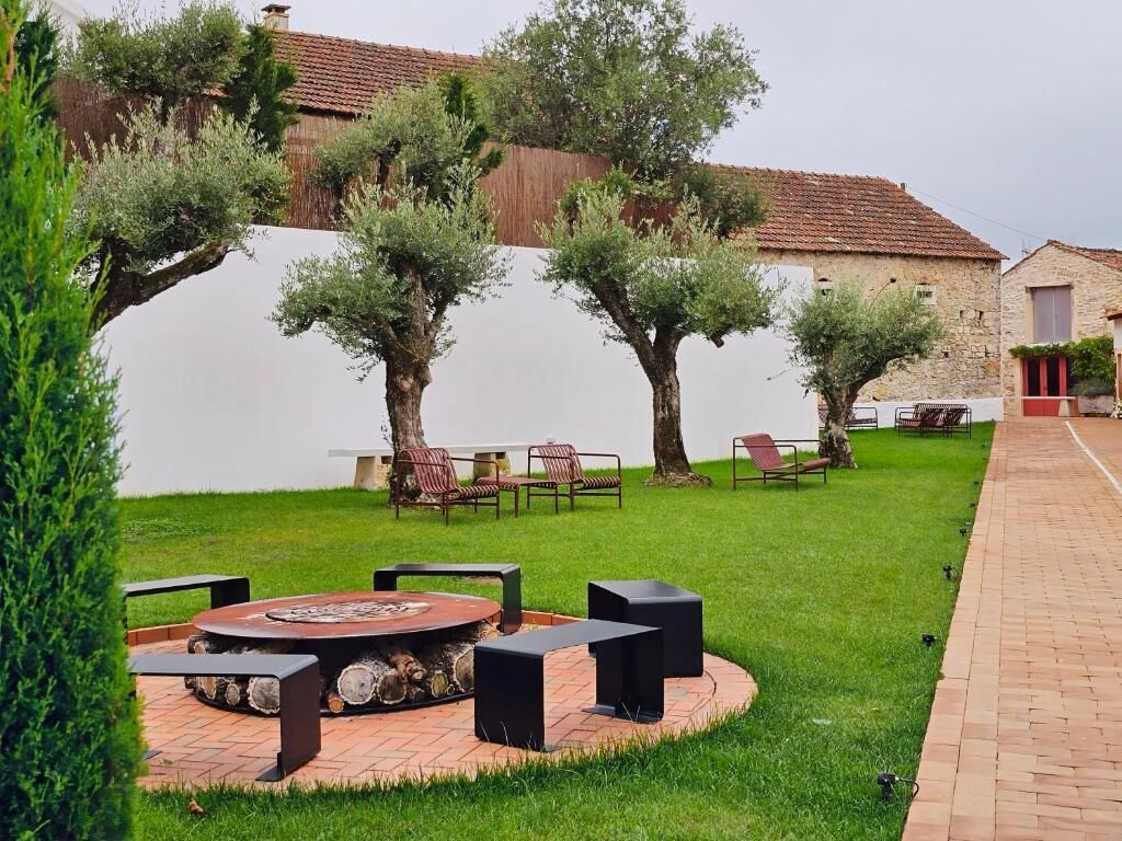 A patio with a circular fire pit, outdoor seating, and a brick pathway.