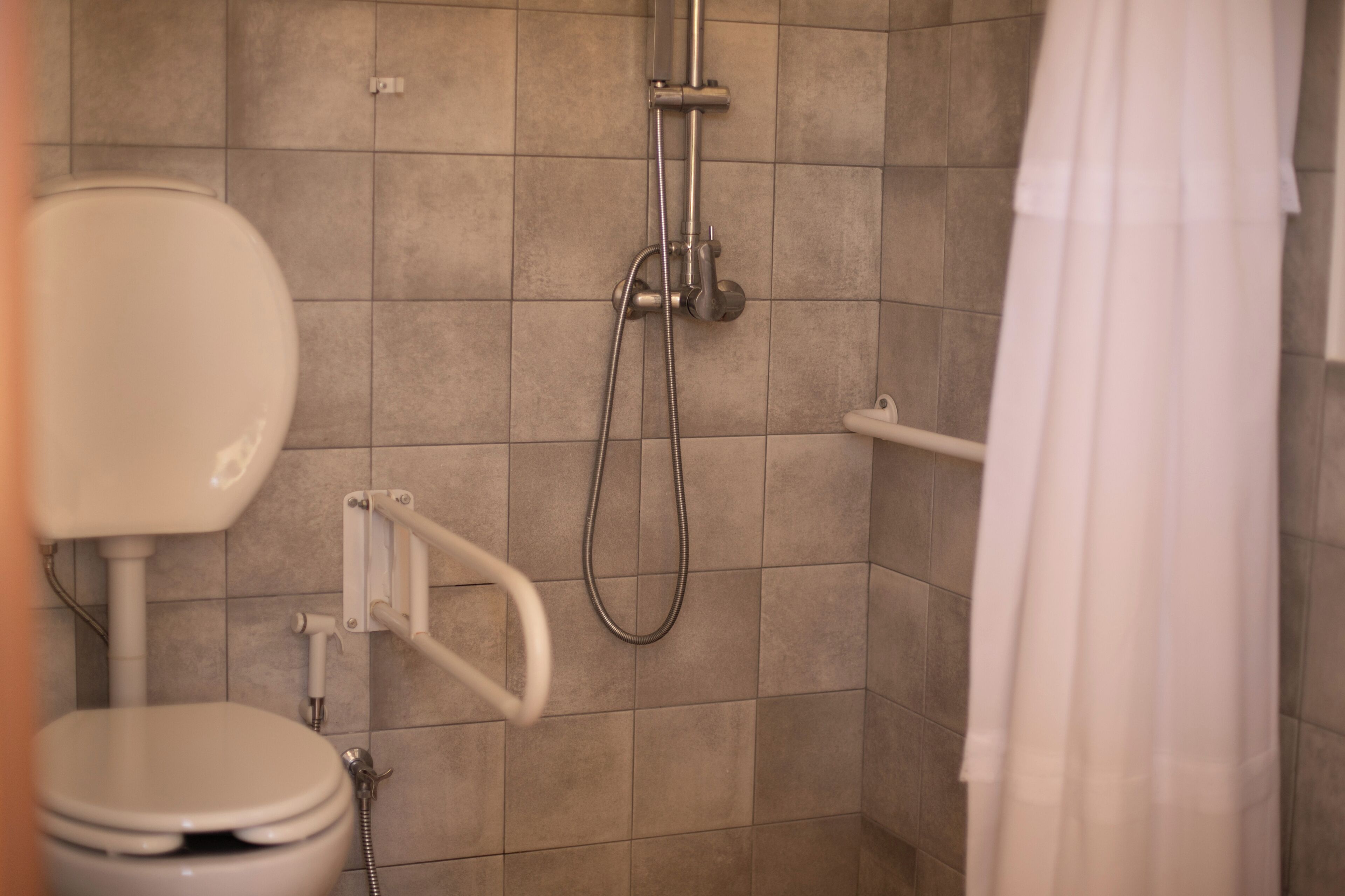 Une salle de bain avec des toilettes, une douche et un rideau.