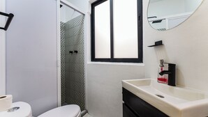Une salle de bain comprenant des toilettes, un lavabo et un espace douche.