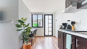 A modern kitchen with dark cabinets, a marble countertop, and a potted plant. - Loft con terraza en CDMX (Narvarte) (Ciudad de mexico)