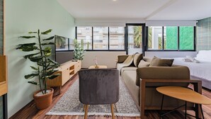 A modern living room with a sofa, a small table, a TV, and a potted plant. - Loft con terraza en CDMX (Narvarte) (Ciudad de mexico)