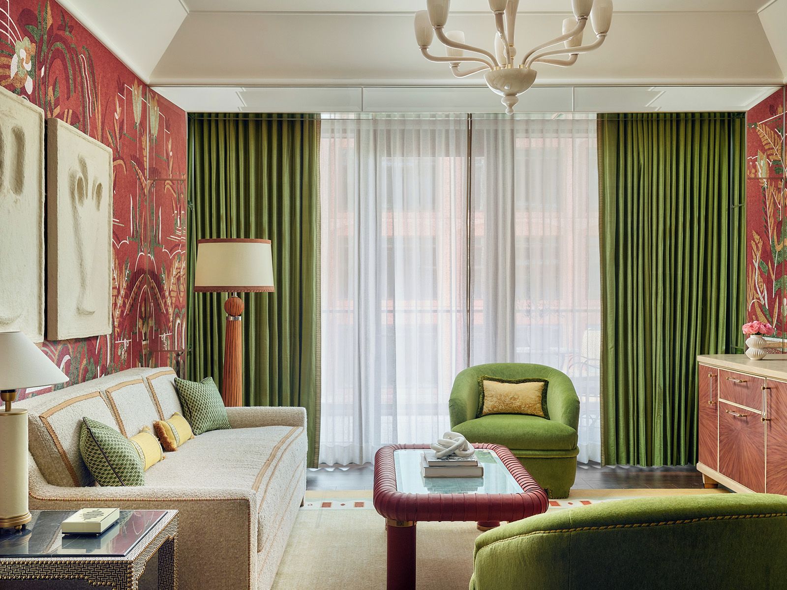A room with a sofa, armchair, and ottoman, a lamp, and a chandelier.