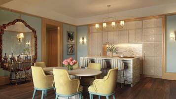 A dining area with a round table and four chairs, a kitchen with marble countertops, and a large mirror with a decorative frame.