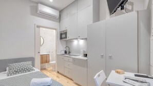 A compact bedroom with a bed, bedside table, and a small desk with a chair. - FindMe inPorto Bonfim 0T (Porto)