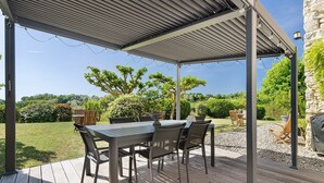 An outdoor patio with a covered table and chairs, surrounded by a garden. - Guest Room “Aubergine” with Shared Pool, Near Sarlat (Proissans)