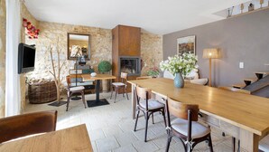 A dining area with a wooden table, chairs, a fireplace, and a television. - Guest Room “Aubergine” with Shared Pool, Near Sarlat (Proissans)