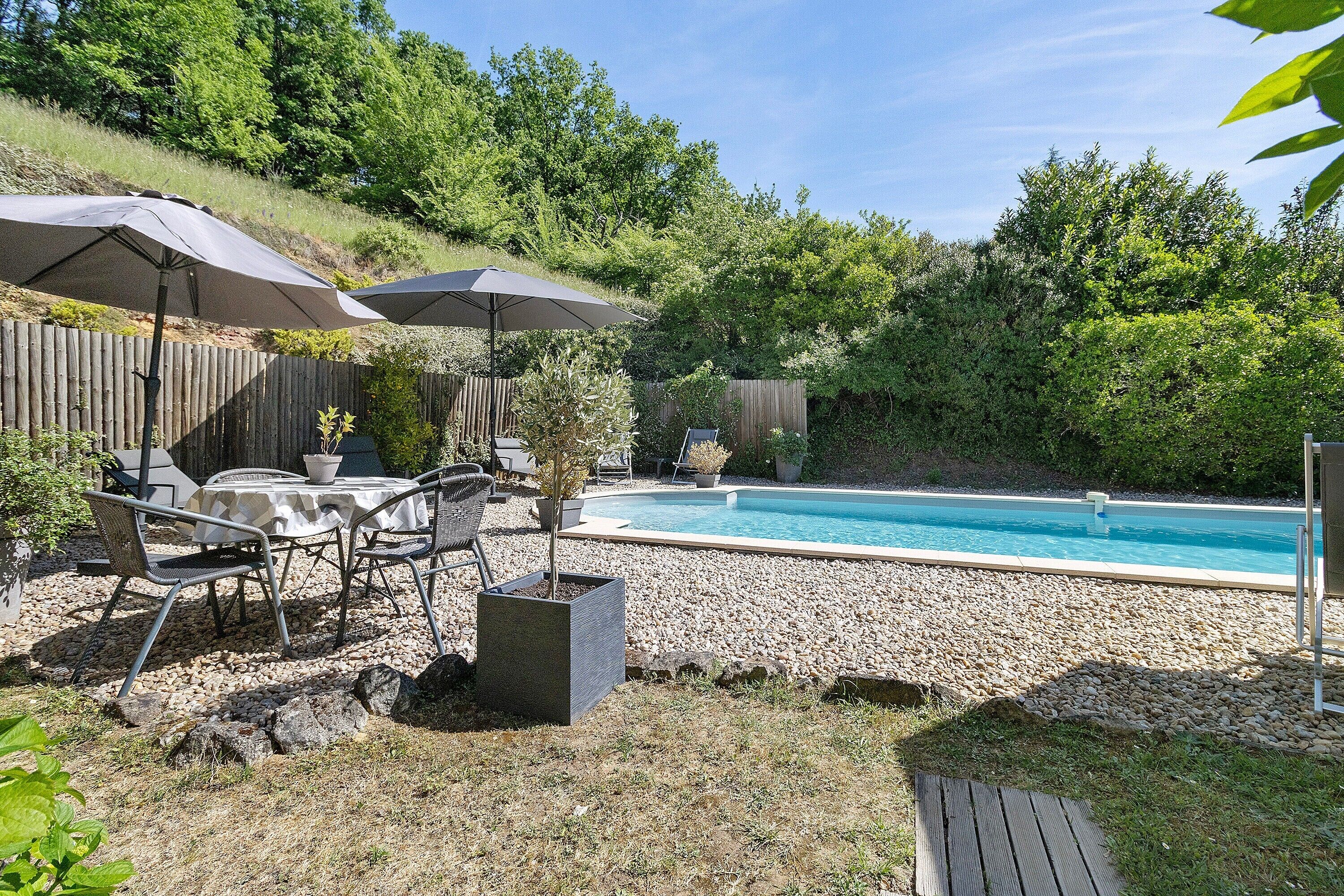 Un jardin avec une piscine, du mobilier d’extérieur et une terrasse en bois.