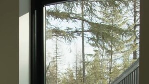 Un edificio moderno con il terreno innevato e una porta visibile attraverso una finestra.