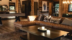 Een ruime woonkamer met een grote modulaire bank, een houten salontafel en een vloerkleed met dessin.
