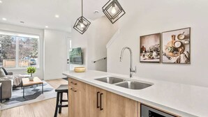 Eine moderne Küche mit einer Spüle, Holzschränken und Pendelleuchten.