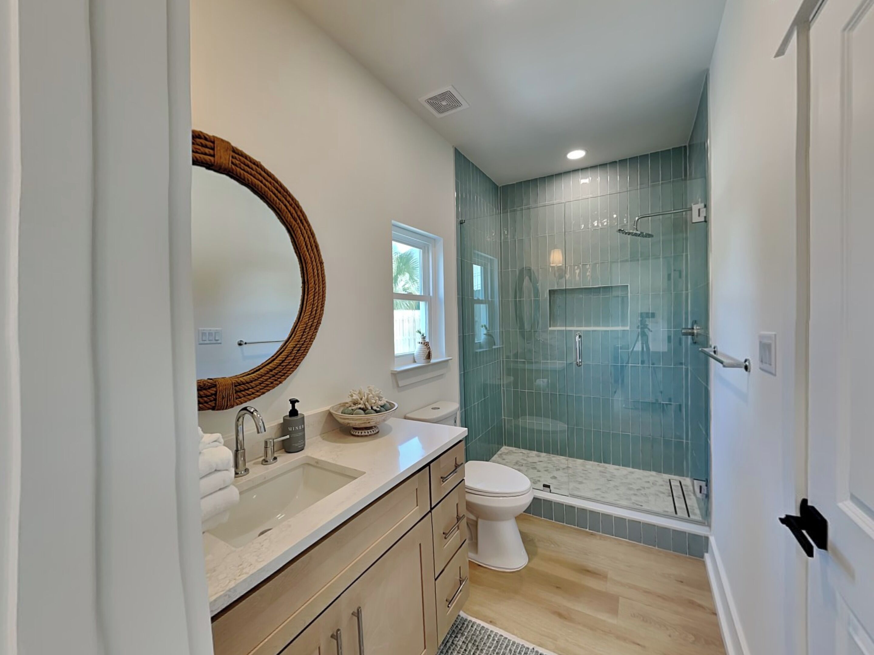 Une salle de bain moderne avec un grand miroir, un lavabo, des toilettes et une douche à parois de verre.