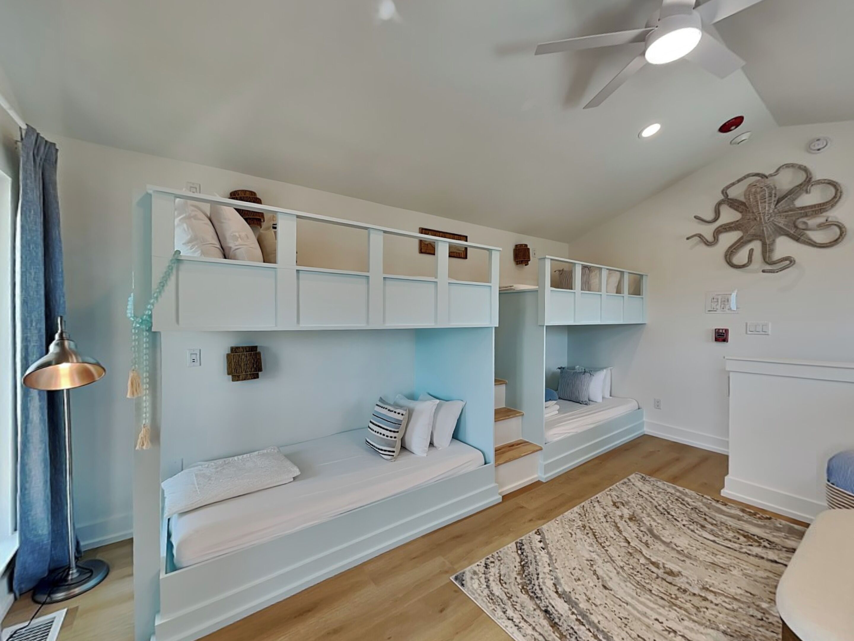 A room with bunk beds, a floor lamp, a rug, and a wall decoration.