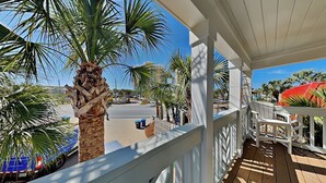 Een balkon met uitzicht op palmbomen, een witte reling en een houten terras.